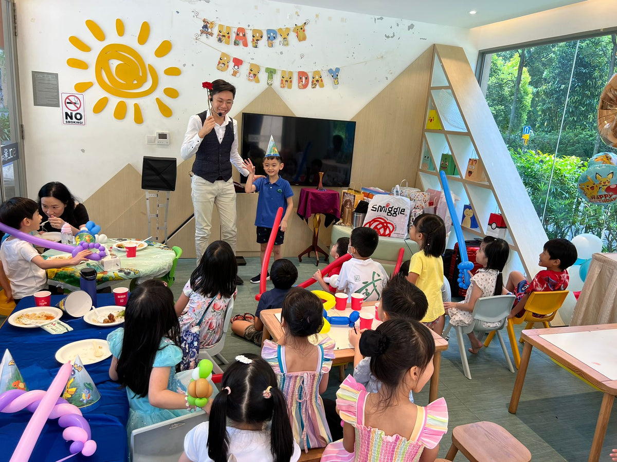 A child helping the magician during a birthday magic show while other children watch