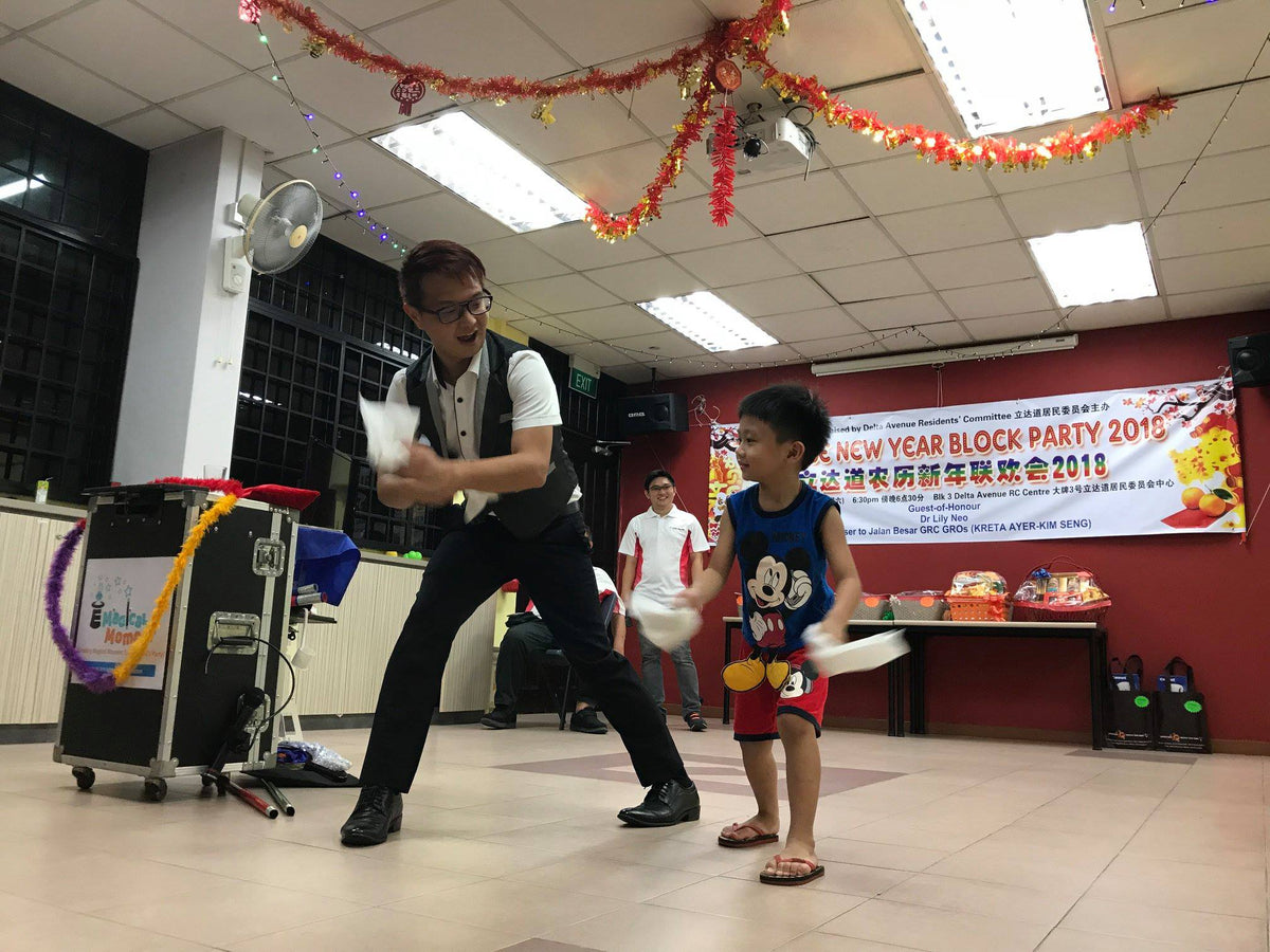 A boy helping the magician perform a trick at a community celebration