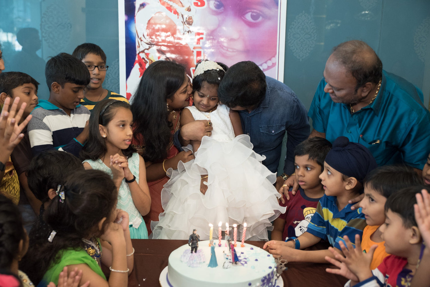 Parents kissing their daughter beside her birthday cake