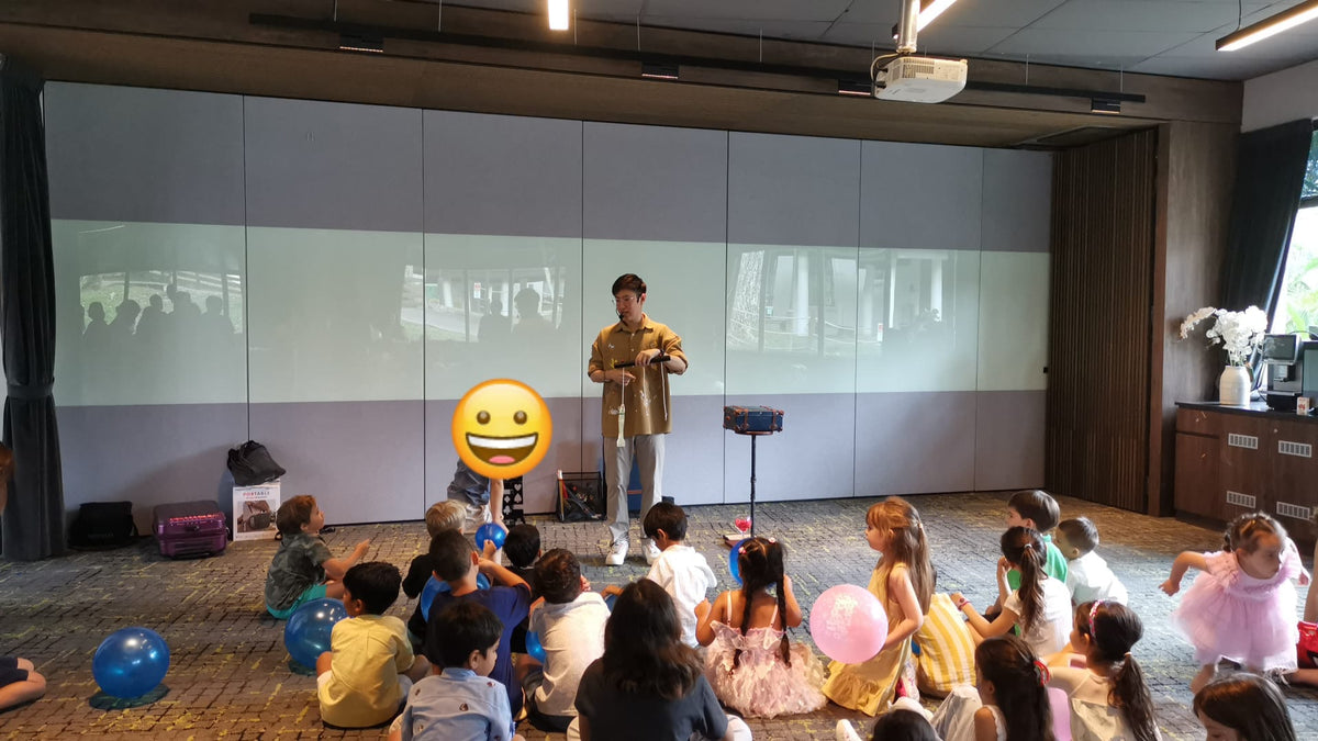 Children gathered around a magician performing an indoor magic show