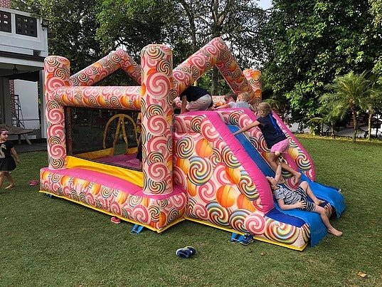 Children playing on a colourful bouncy castle with an inflatable slide