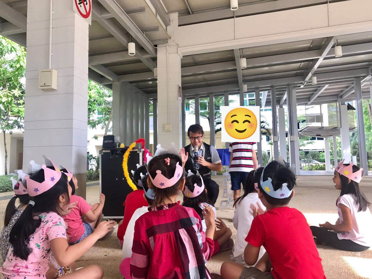 Children wearing paper crowns watching a kids magic show in Singapore
