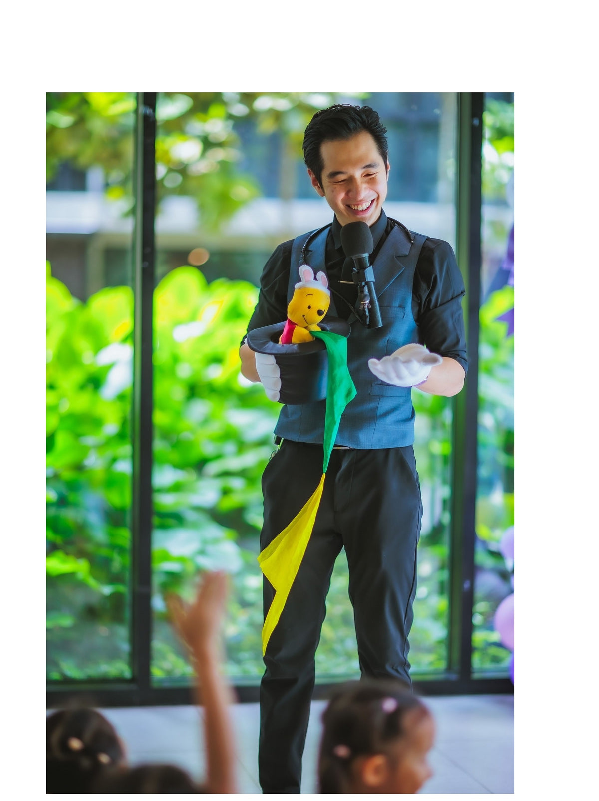 Magician holding a top hat and colourful props for a kids magic show