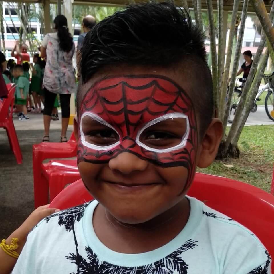 Smiling child with a red and black Spider-Man face painting design